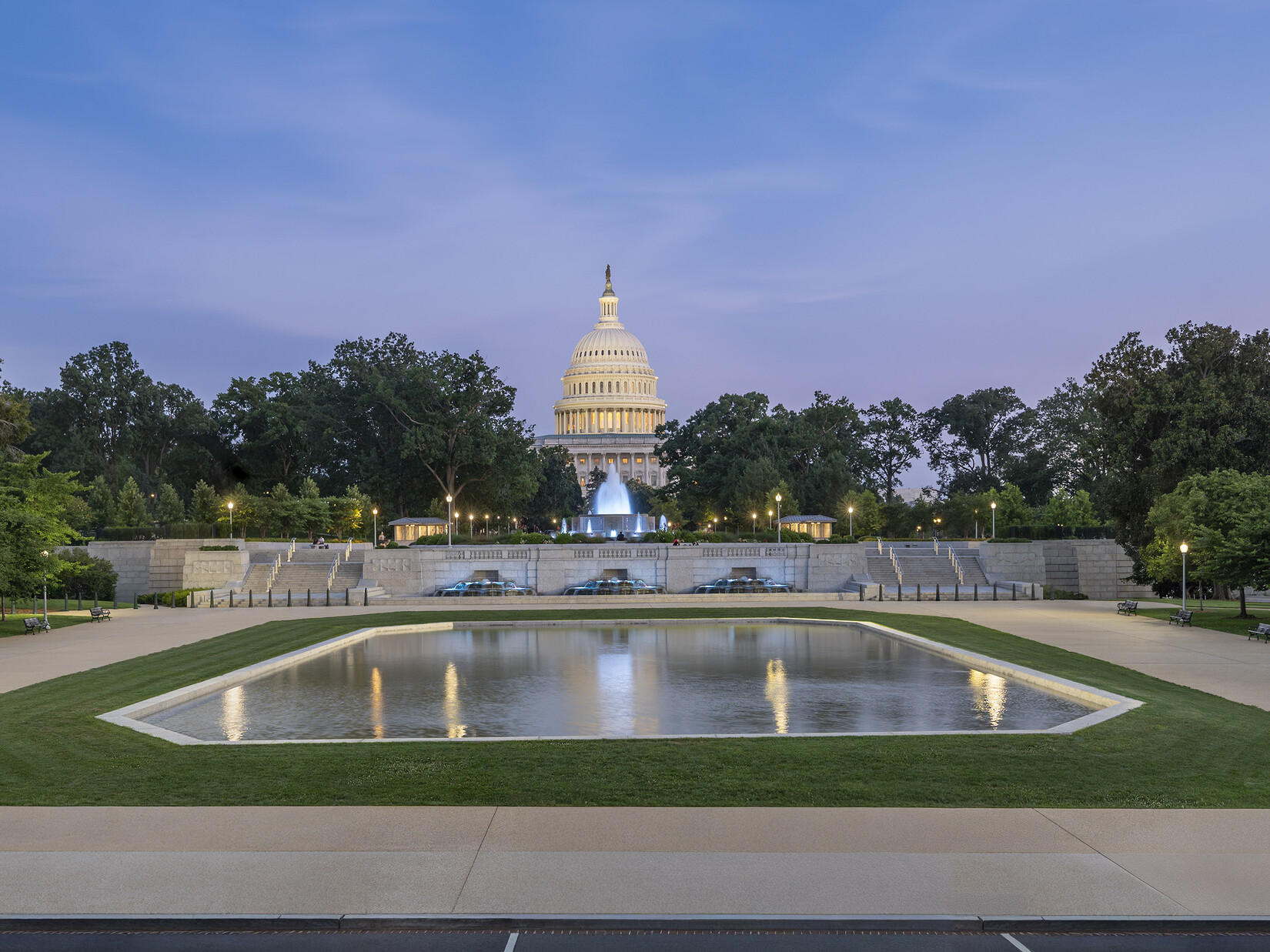 Wide shot of reflection pool with the Capitol building in the background against a sunset sky.