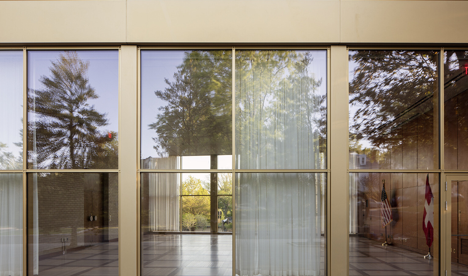 Large floor to ceiling windows outlined in brushed gold frames, looking into an empty room