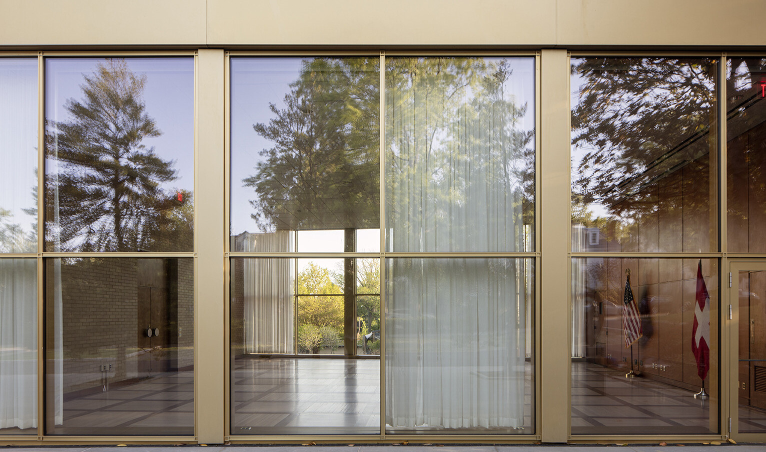 Large floor to ceiling windows outlined in brushed gold frames, looking into an empty room