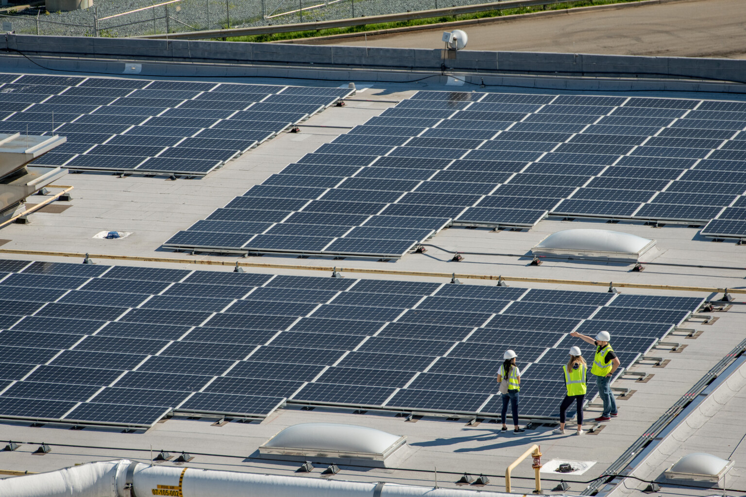 rooftop solar panel array roof mounted three engineers stand over