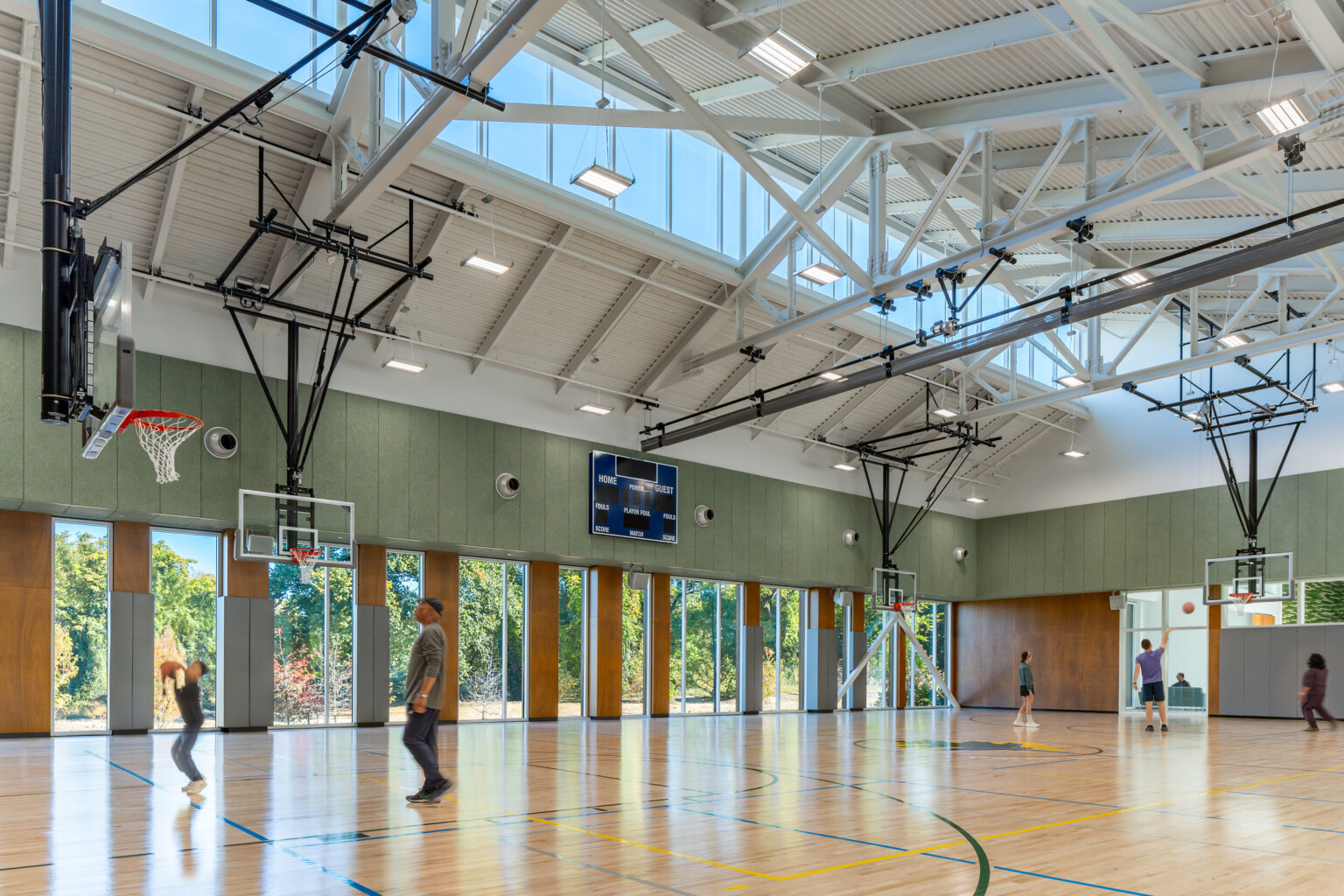 Indoor basketball court with hoops suspended from the ceiling filled with people playing basketball.