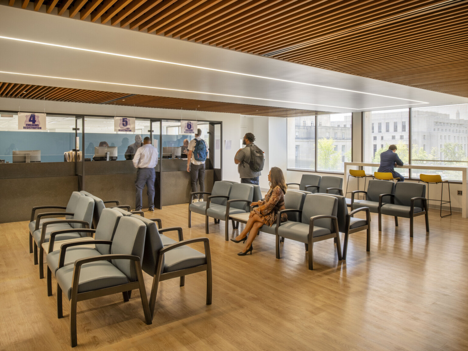 A modern office waiting area with chairs, a service counter, and large windows.