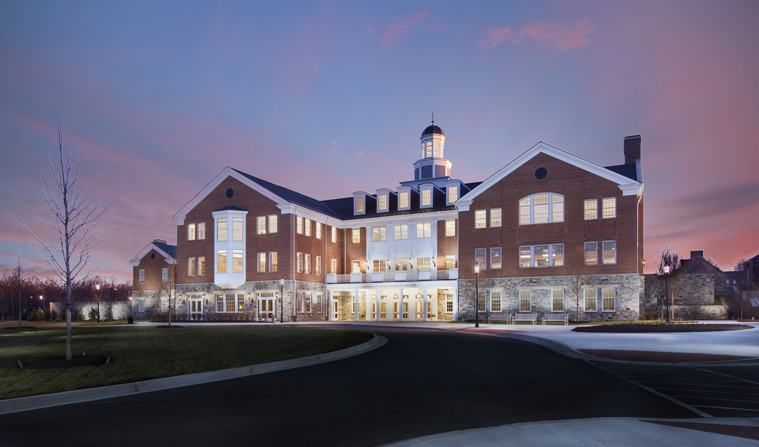 Exterior image of the Edward St. John Student Center at McDonogh School showing a brick and stone exterior with white accents and railings
