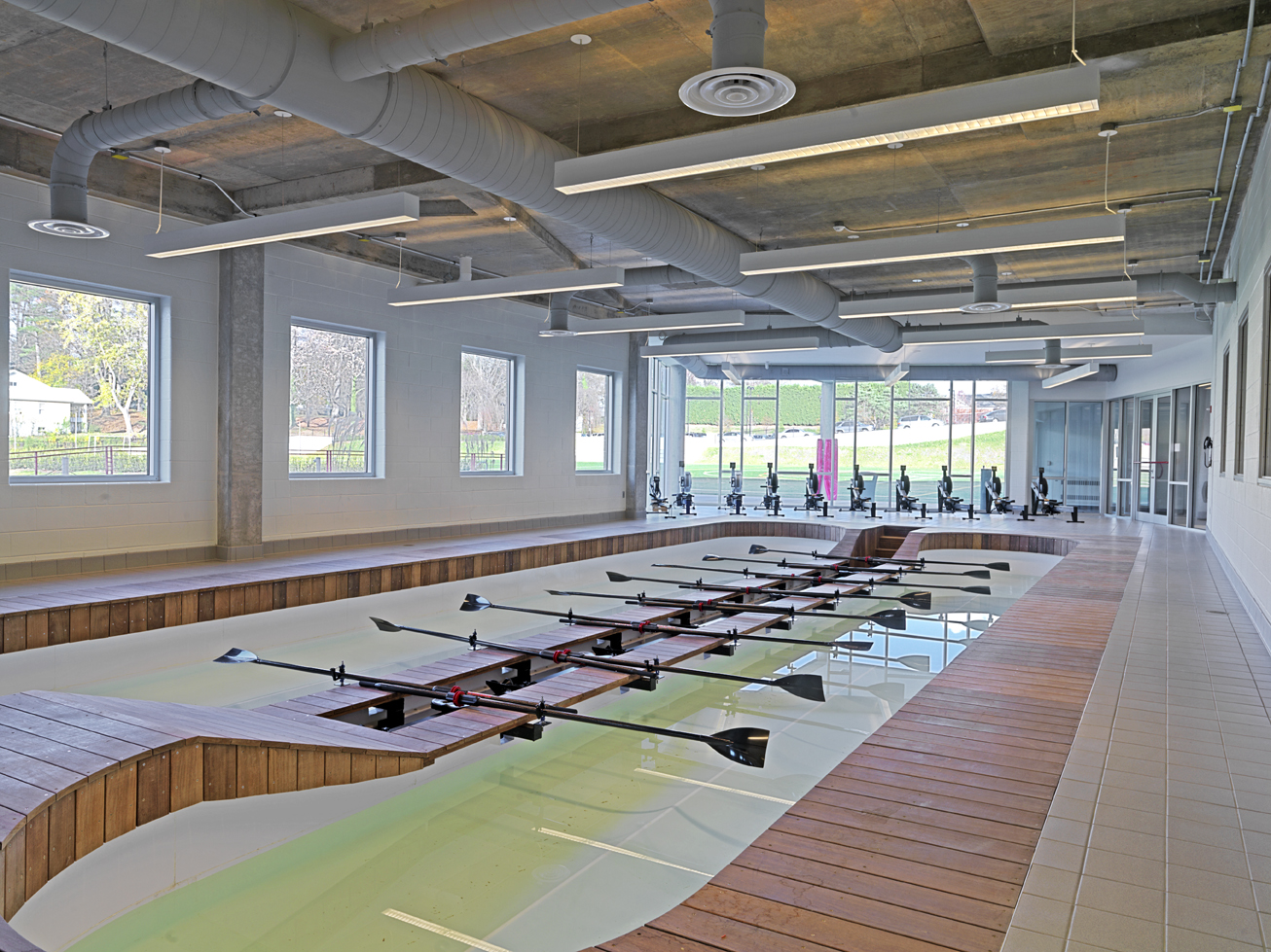 Indoor pool lined with wood and tile divided by rowing equipment