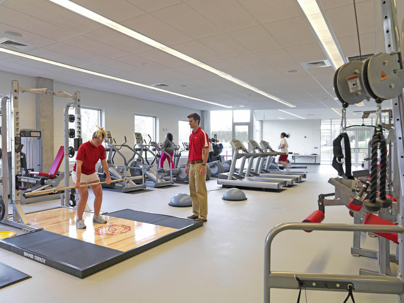 Indoor exercise gym filled with equipment and people exercising
