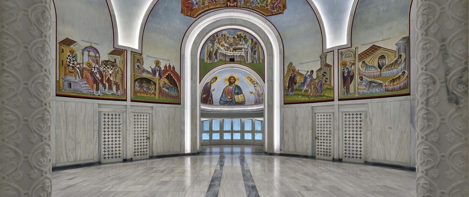 Interior of the St. Nicholas Greek Orthodox Church NYC showing intricate paintings on the walls flaking an archway