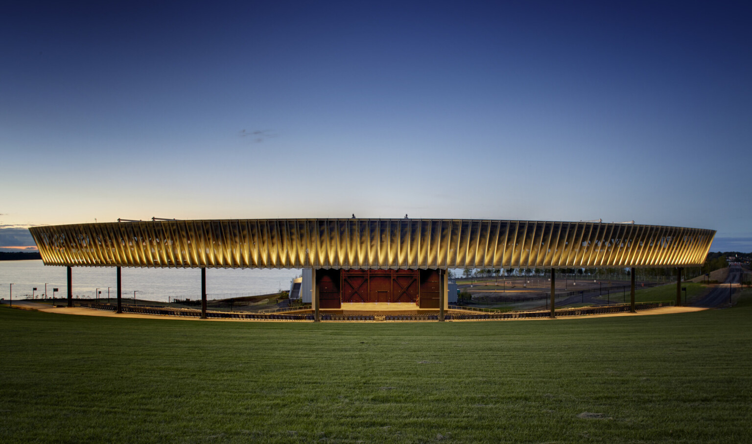 Paneled fascia partially illuminated from bottom over an amphitheater next to a body of water