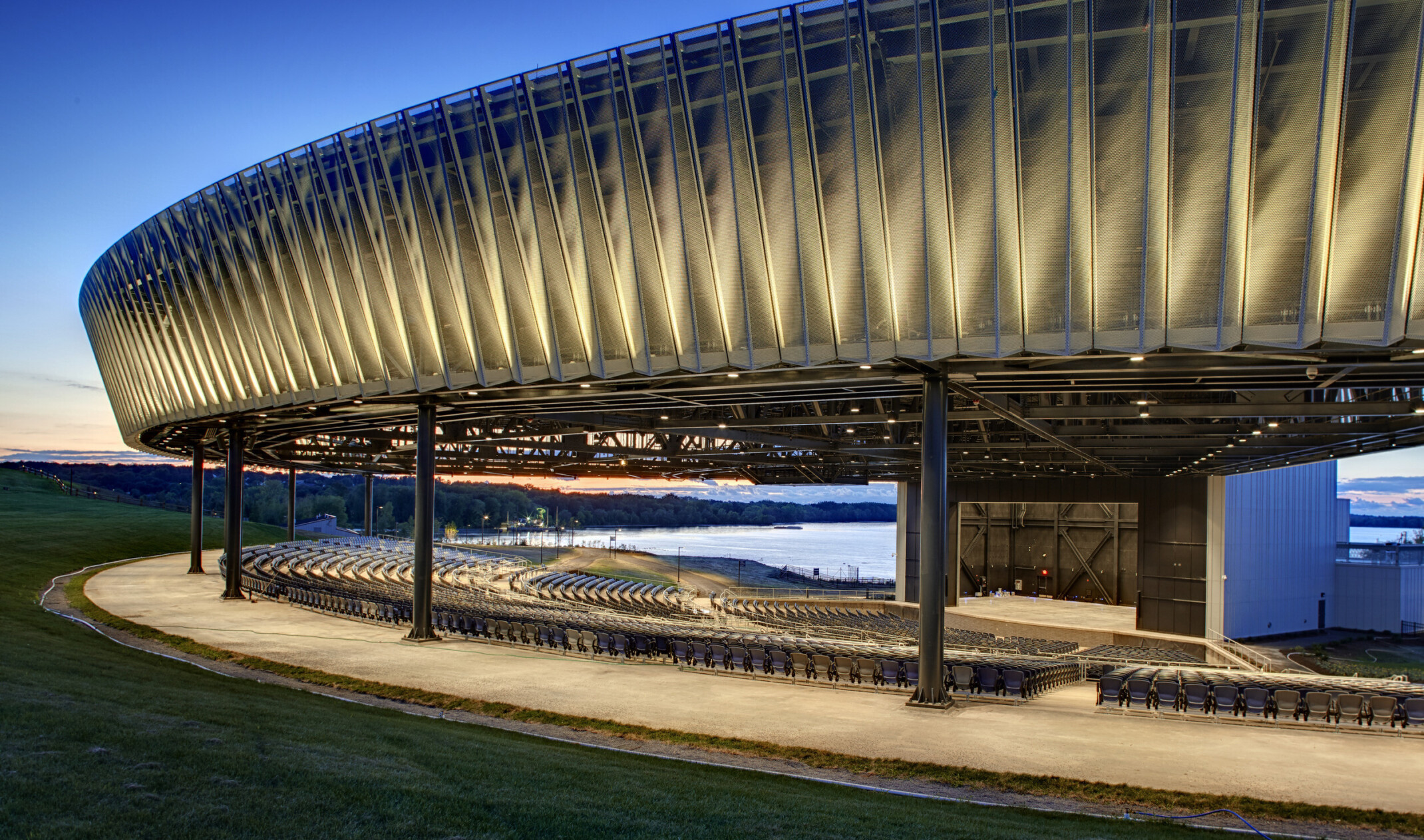 Evening view of perforated and sculpted outdoor amphitheater canopy at Onondaga Lakeview Amphitheater
