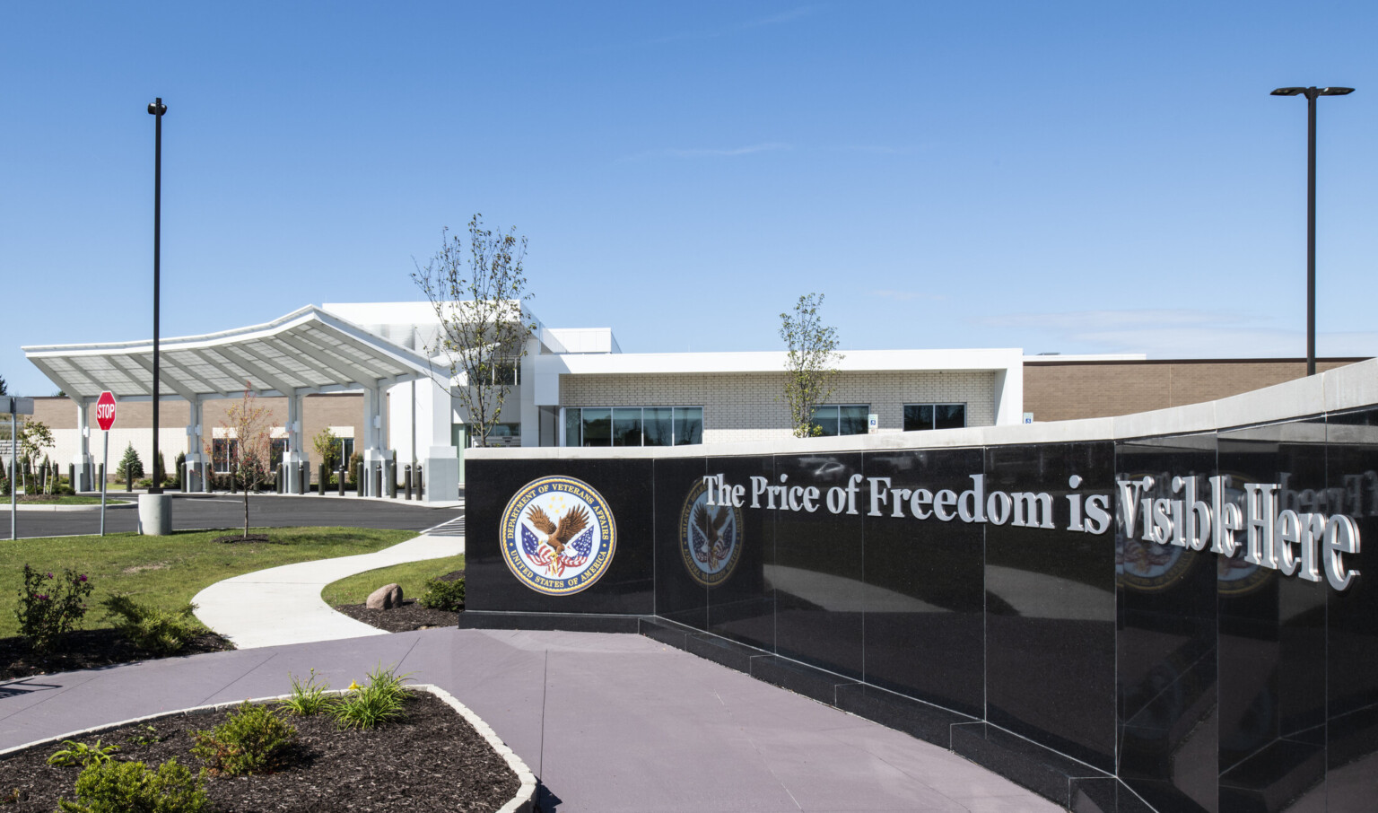 Partial view of black sign with Department of Veteran Affairs logo in front of building entry with angular awning