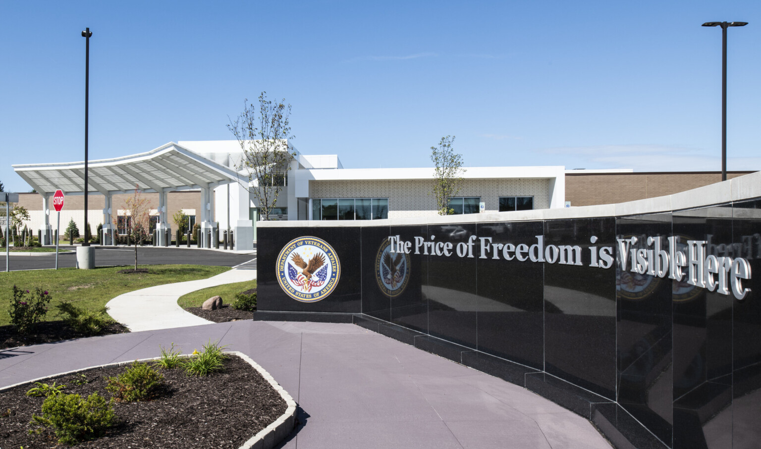 Partial view of black sign with Department of Veteran Affairs logo in front of building entry with angular awning