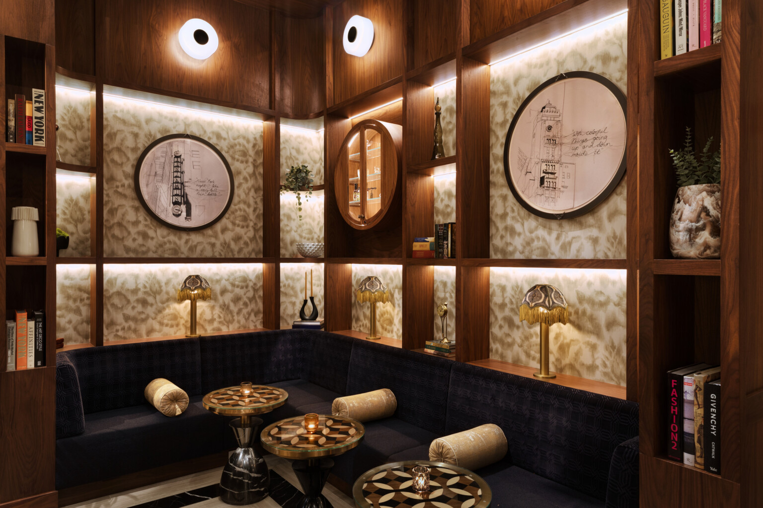 Modern seating area with black velvet bench seating below wooden shelves built into the wall display artwork and other pieces