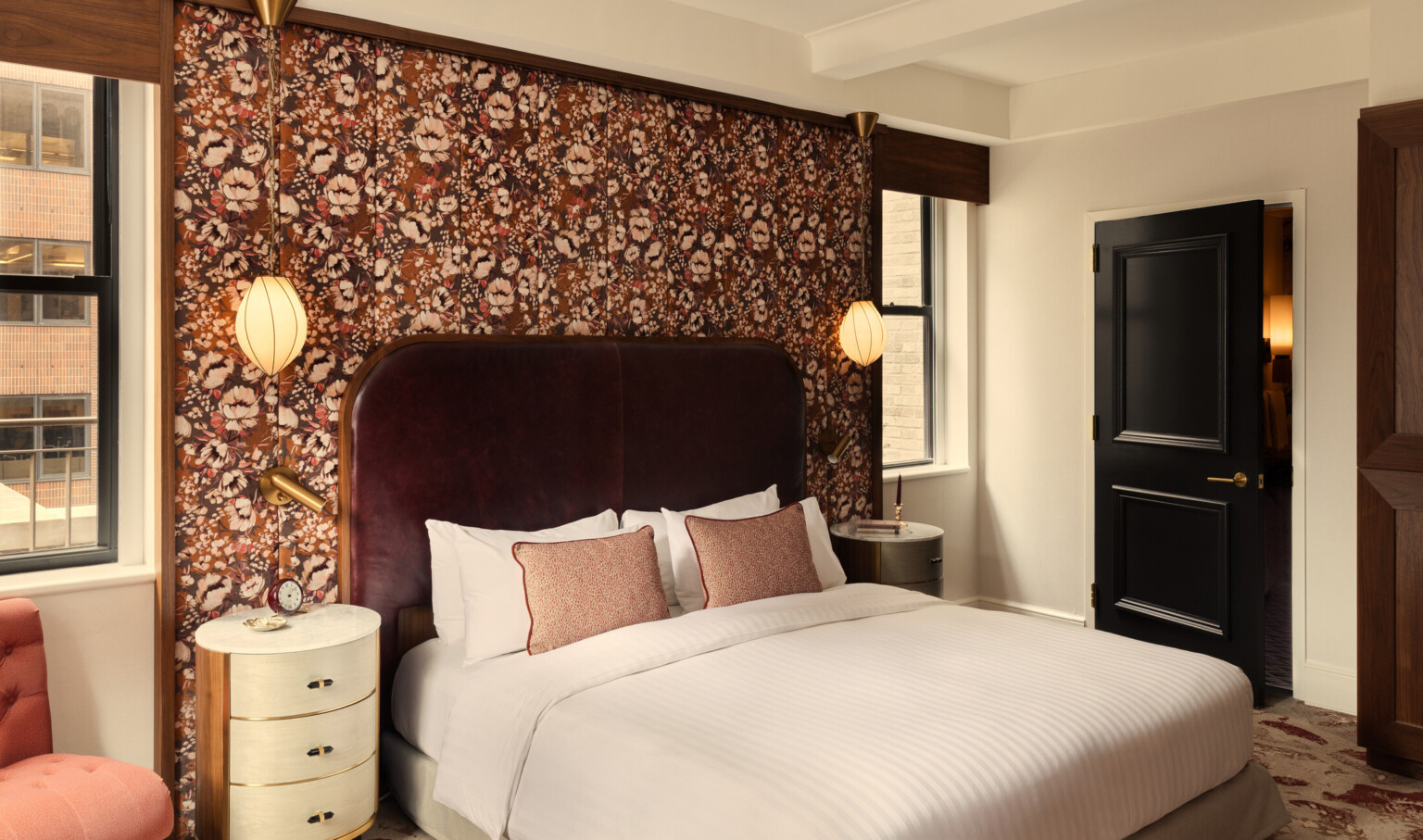 Glamorous hotel room showing wooden doors, orange accent chair, and white bedding Glamorous hotel room showing wooden doors, orange accent chair, and white bedding