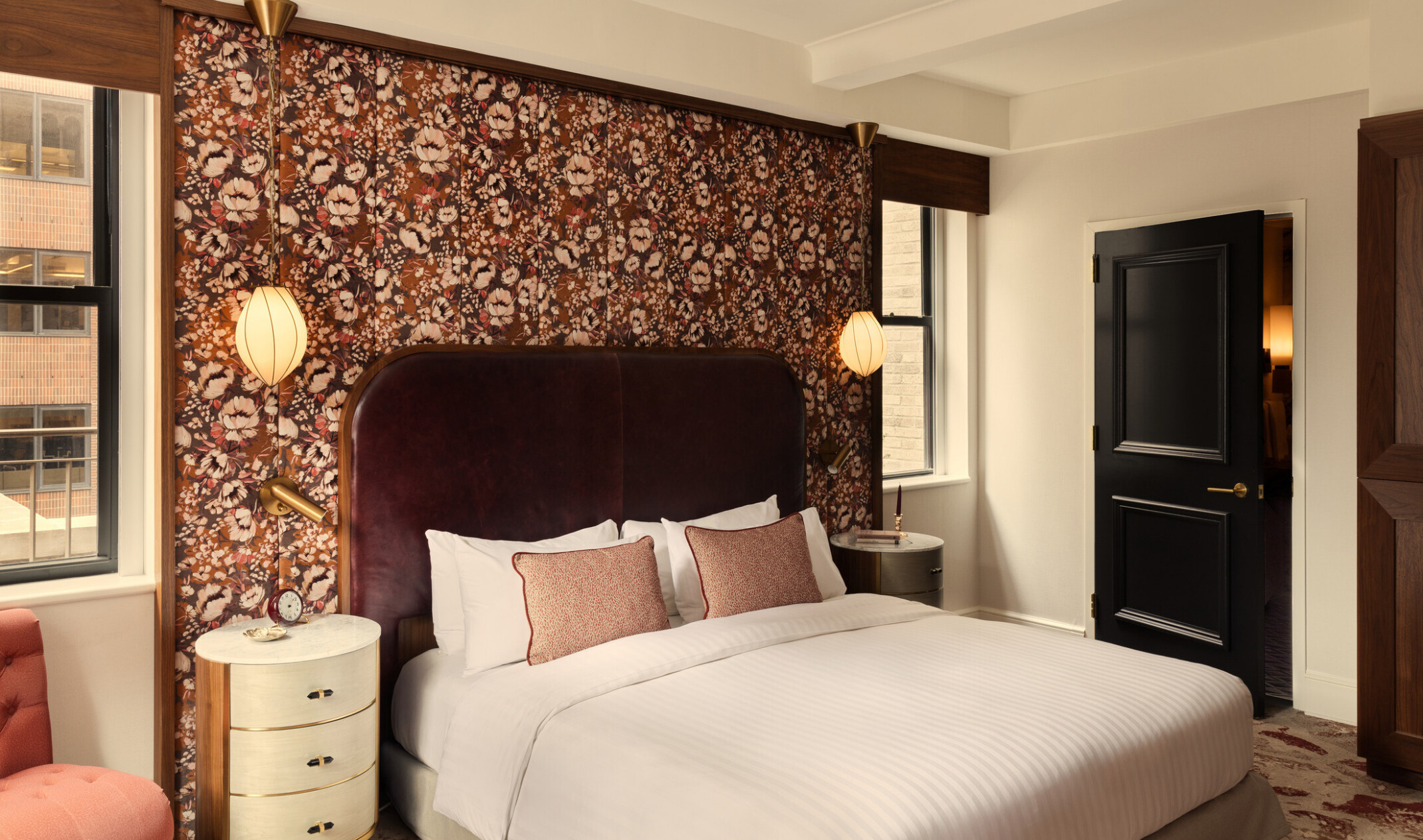 Glamorous hotel room showing wooden doors, orange accent chair, and white bedding