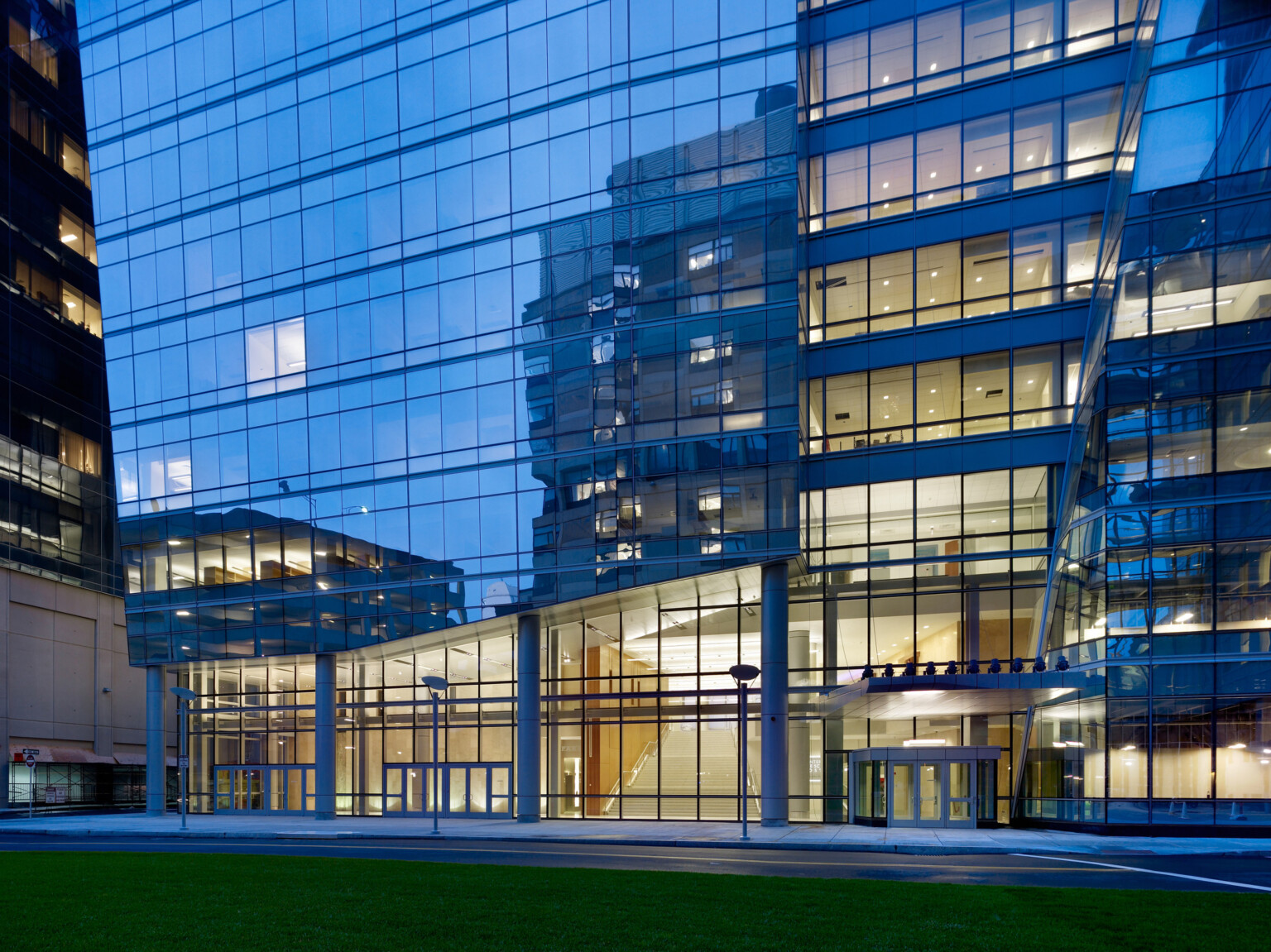 A modern glass medical building supported by large columns with large windows and a reflective surface.
