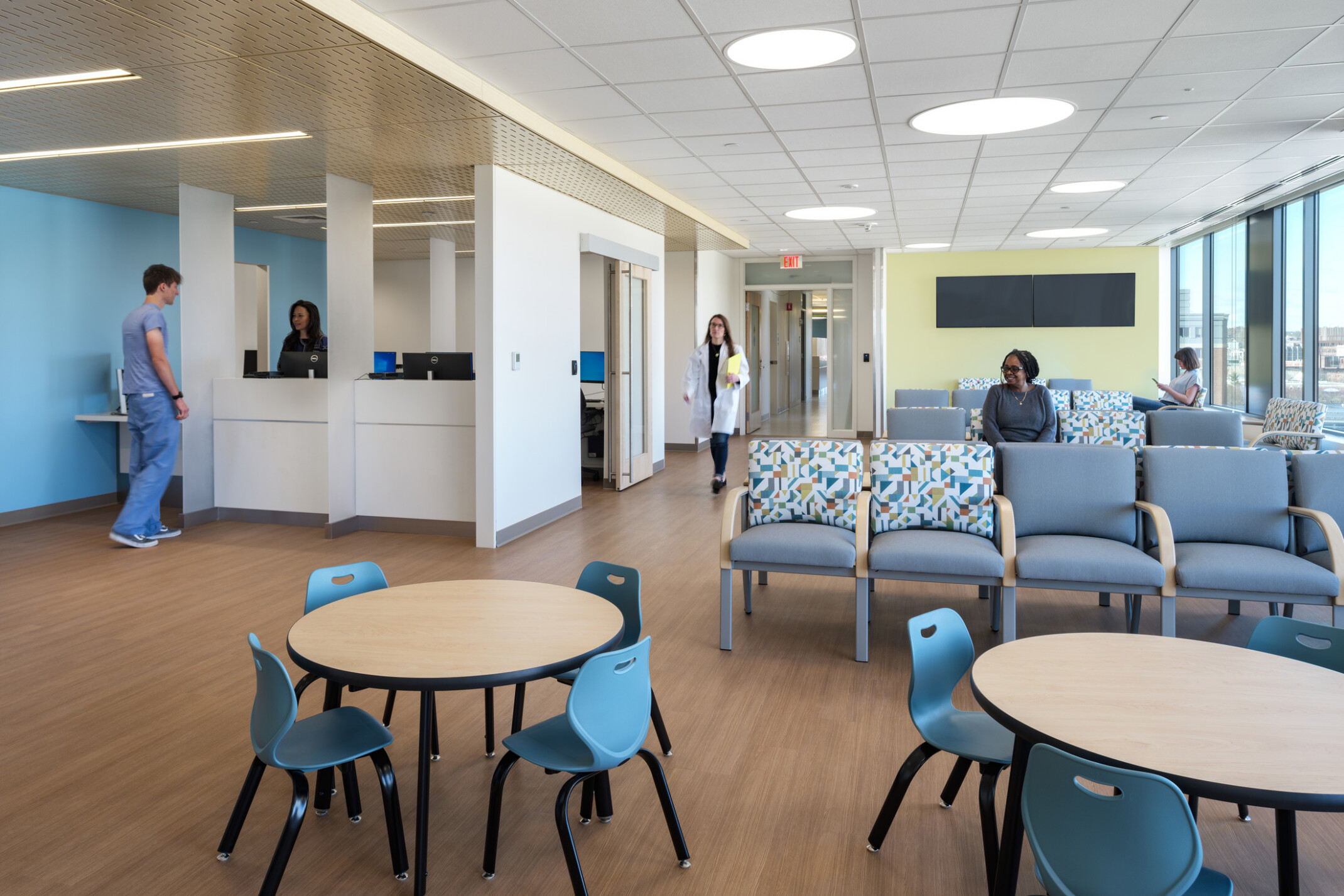 waiting area with couches and tables with a check in desk for medical information