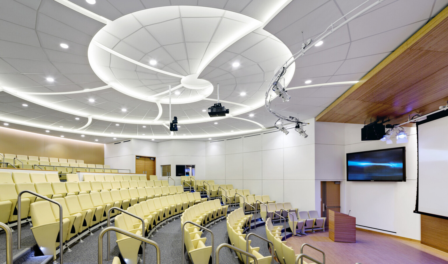 lecture hall at top medical school; ceiling has swirl design mimicking a shell; yellow seats, white walls, wood accents