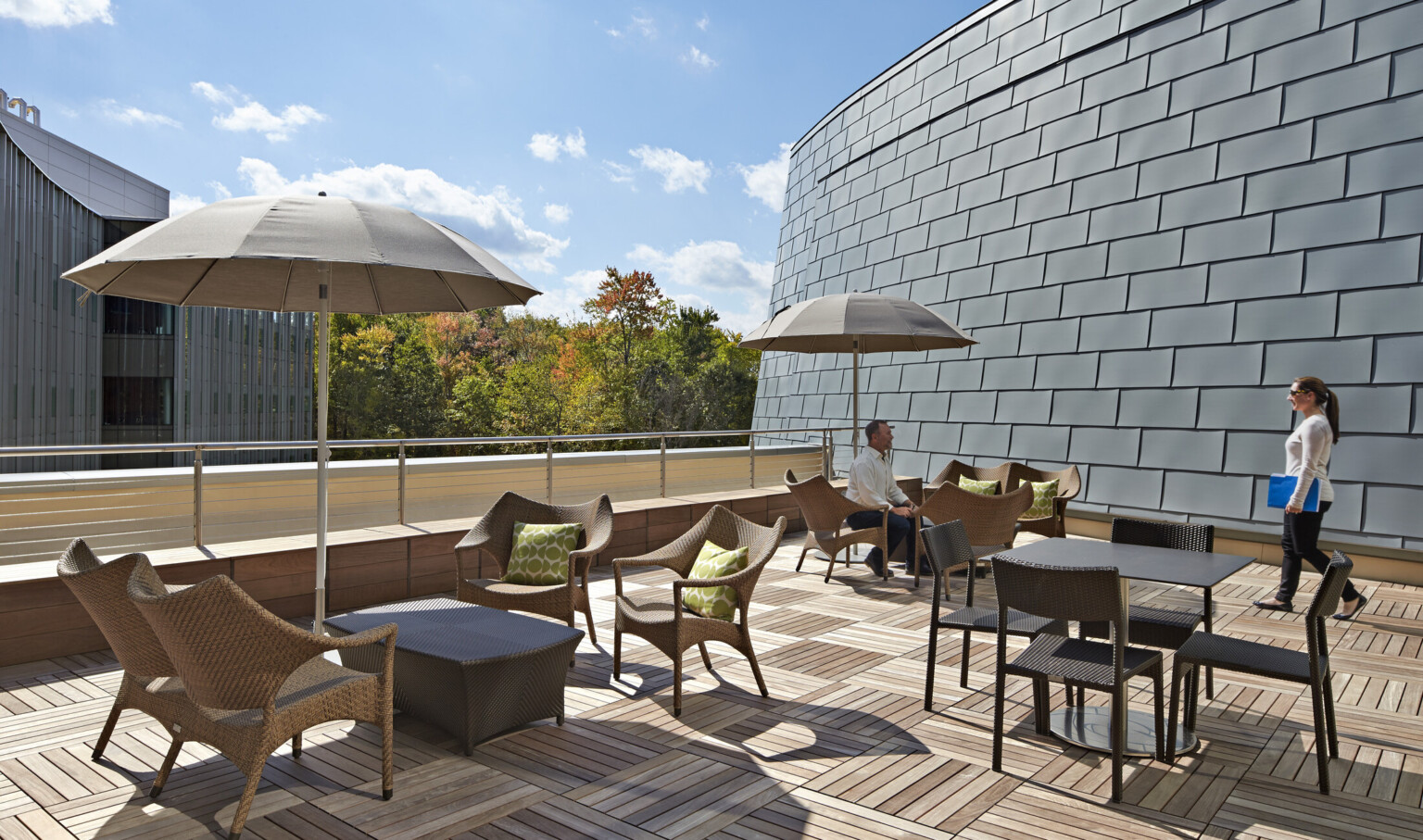 patio with ergonomic wicker seating, umbrellas for shading and grey slate panels along the facade