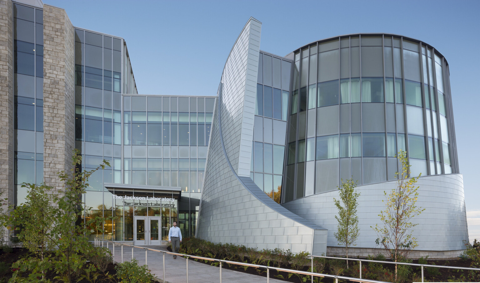 exterior of a modern building with metail facade panels and curved glass windows; sculptural effect created with round structure