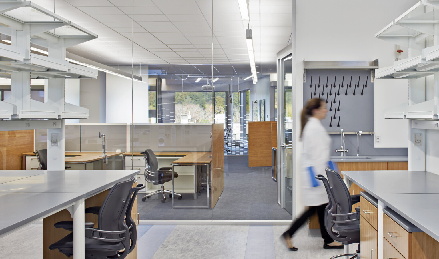 genome lab at JAX Genomic Medicine; woman walking across the area with labs and office spaces in one area separated by glass