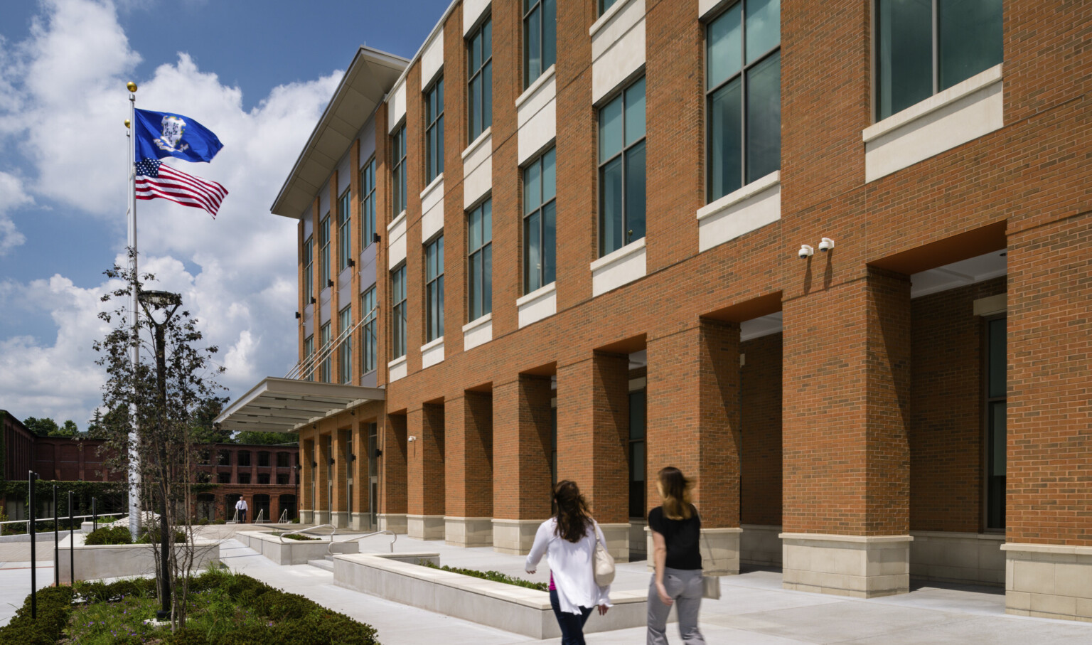 Exterior of brick courthouse with flags waving to left, large windows framed with beveled masonry to right