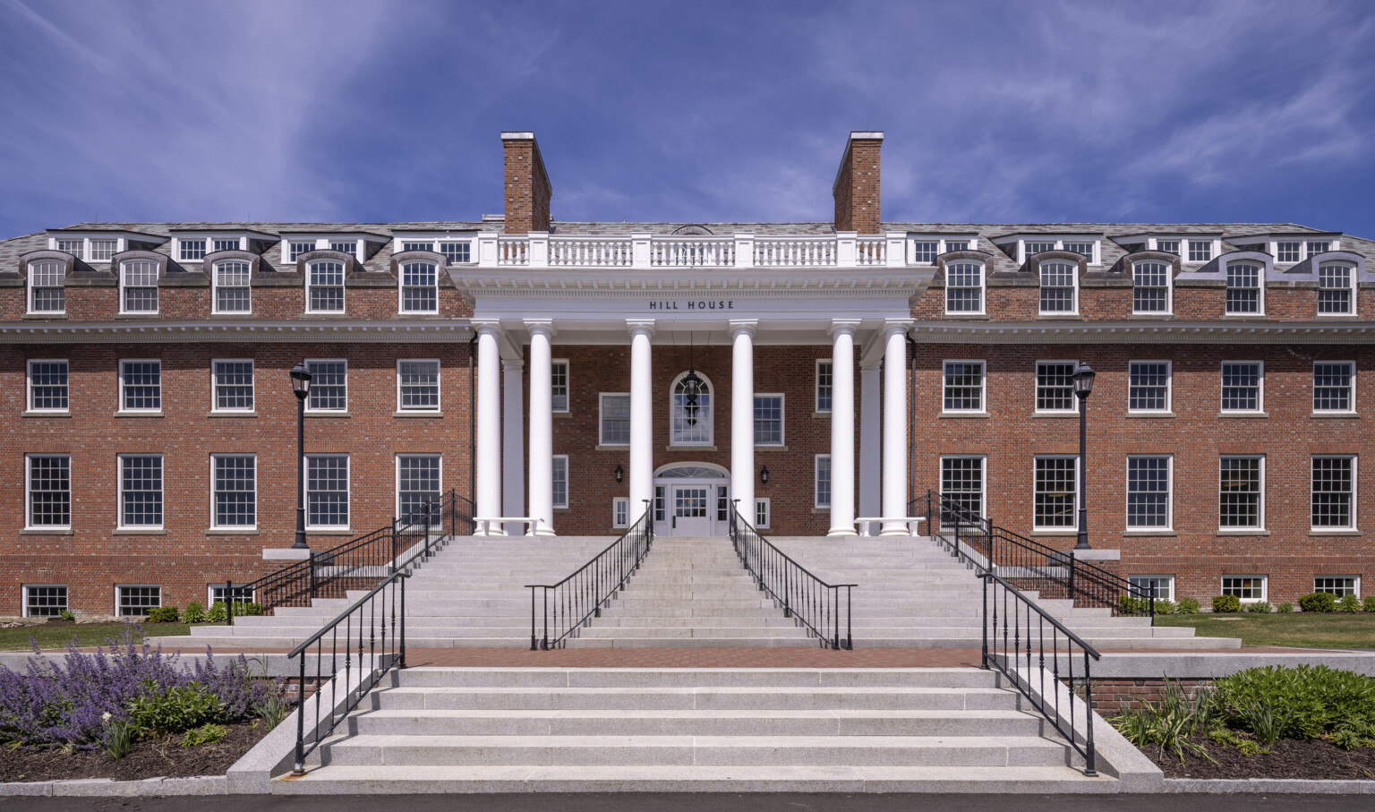 Grey stone front steps with wrought iron rails to column double height entrance of Georgian Revival boarding school dormitory