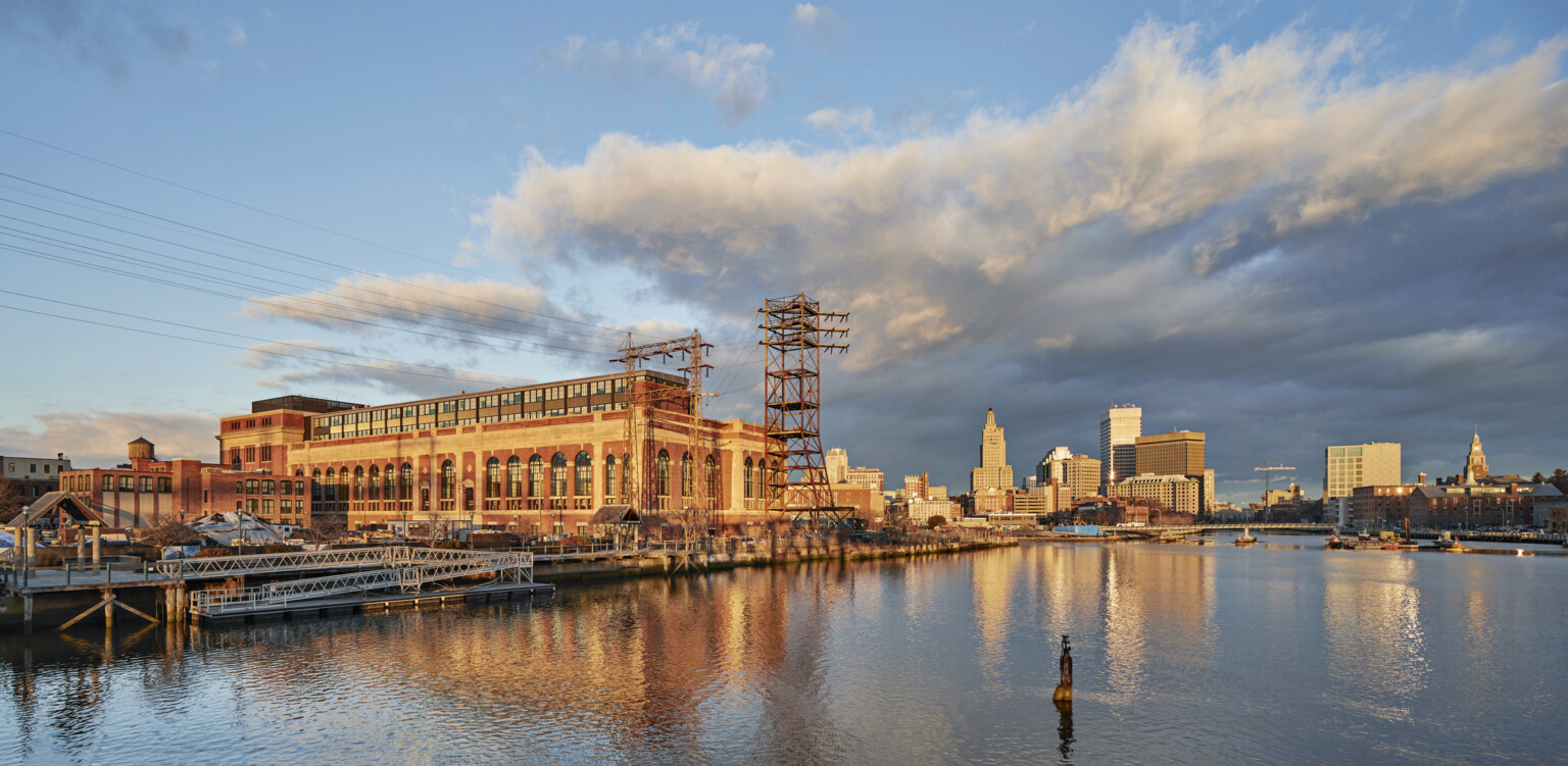 River view of South Street Landing in Providence, RI; adaptive reuse of an old power station into medical training facility; large building with older facade and power lines surrounding