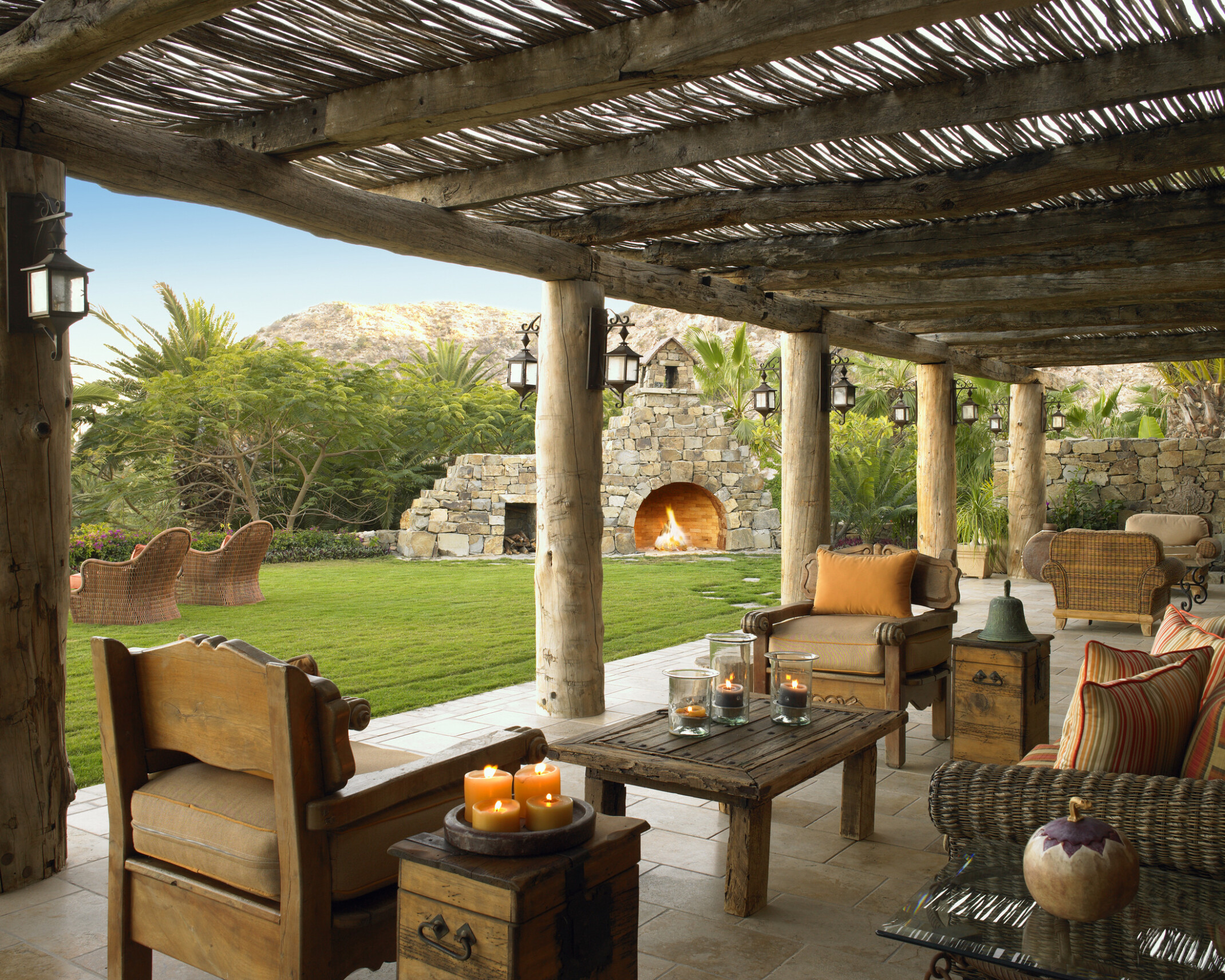 outdoor patio at a golf and beach club in Cabo San Lucas, Mexico; natural materials build out the space for relaxing retreat; stone fireplace in background