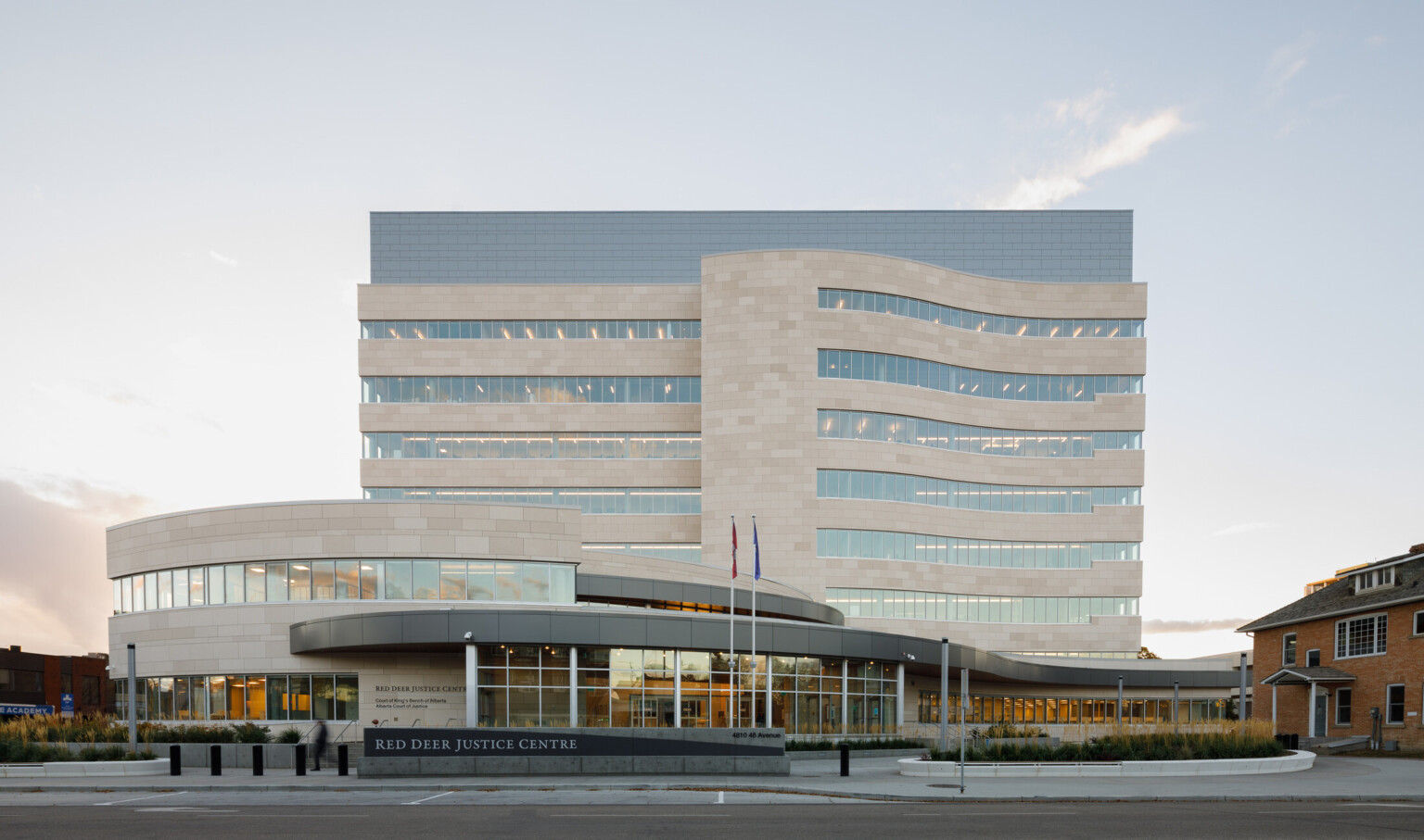 Early evening exterior view from street level of a rectangular nine-story courthouse with a public plaza fronting a curved entrance and lobby.