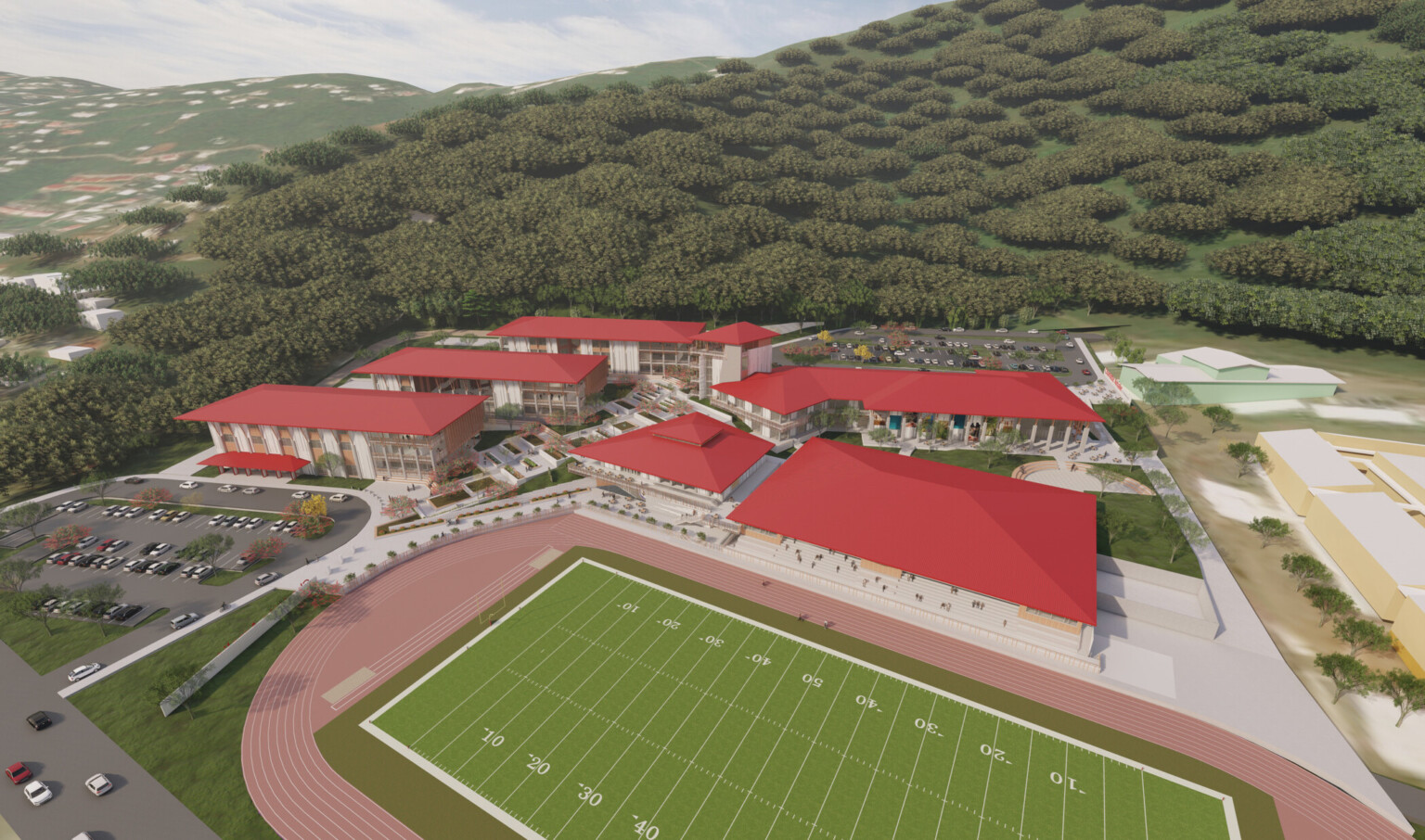 Aerial view of campus. 5 white multistory buildings with red roofs surround walkway and green space. Football field, front