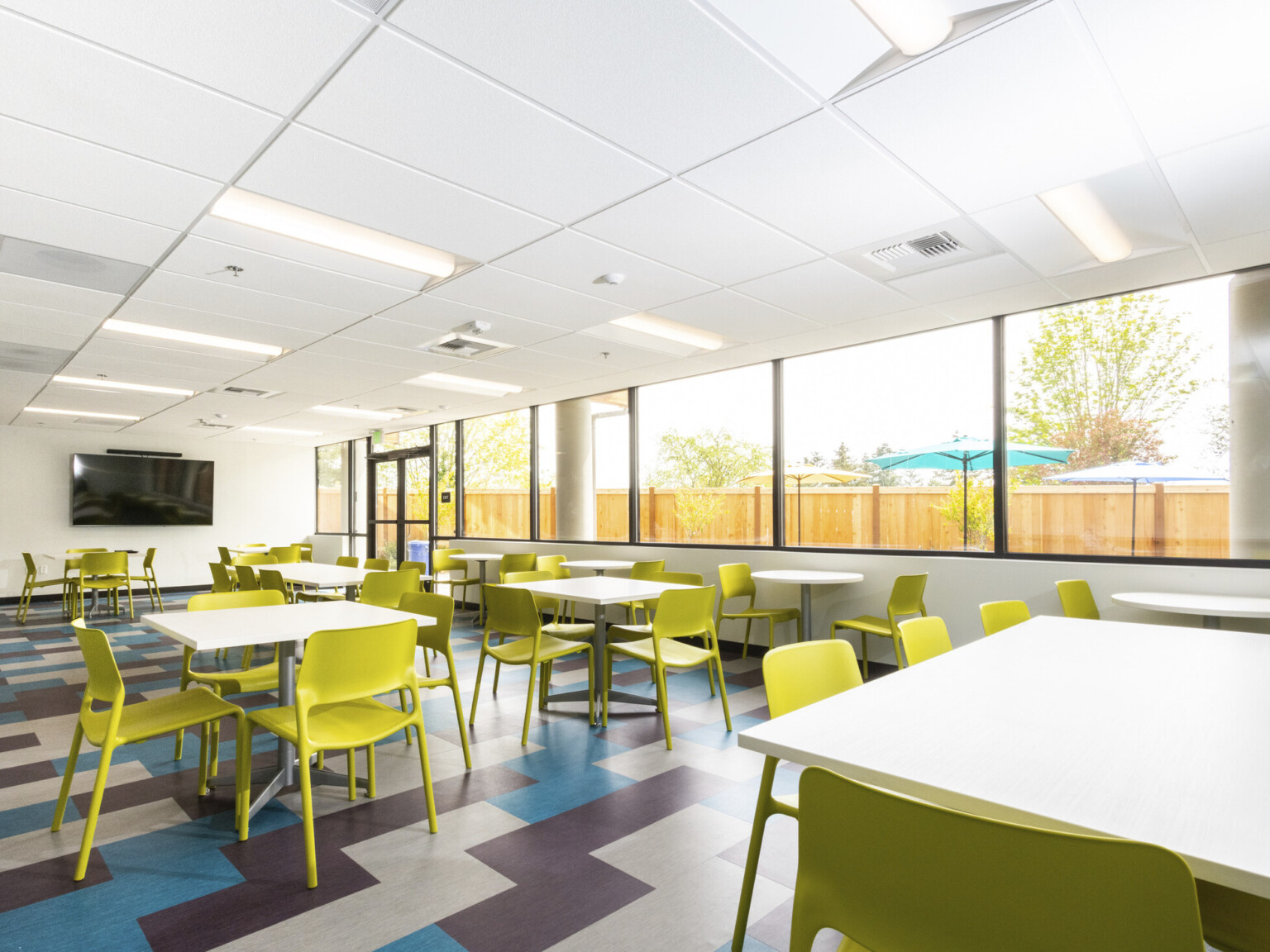 common area with expanse of glass geometric blue purple and tan floors white tables and chartreuse plastic molded chairs