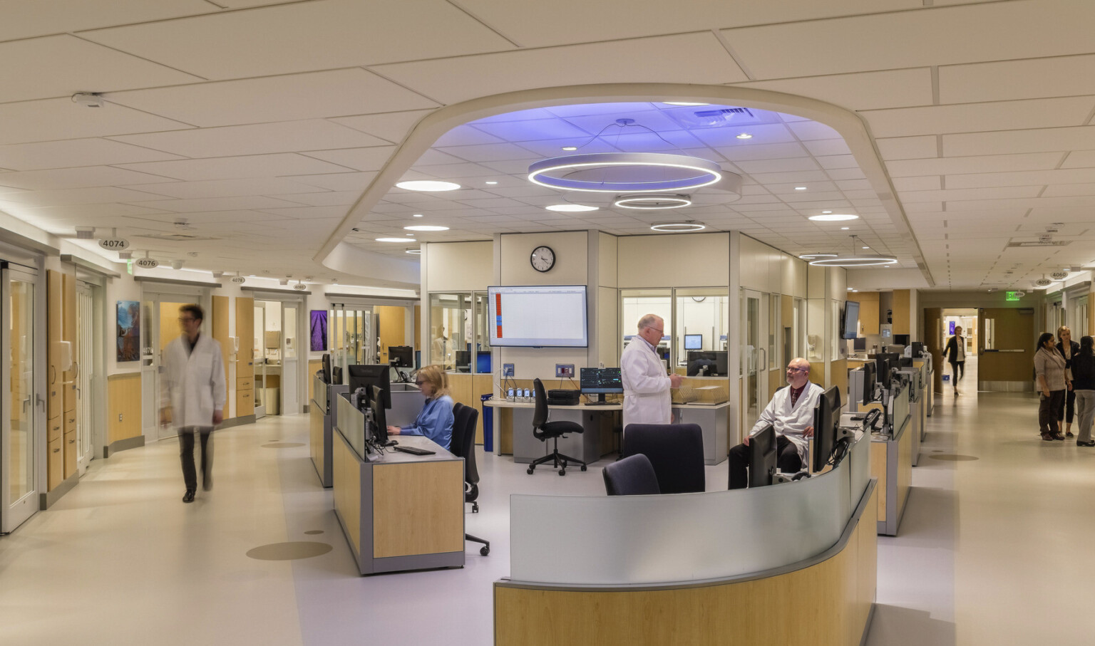 EvergreenHealth Progressive Care Unit with long desk wrapped around corner of hallway with blue and white accent lights above EvergreenHealth Progressive Care Unit with long desk wrapped around corner of hallway with blue and white accent lights above