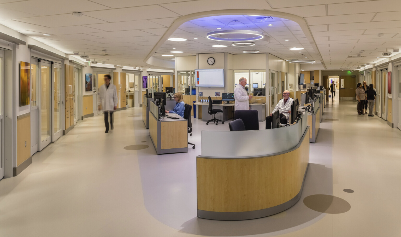 Modernized hospital nurses station, reception area, light birch wood furniture modules, muted wall and flooring palette, well-lit
