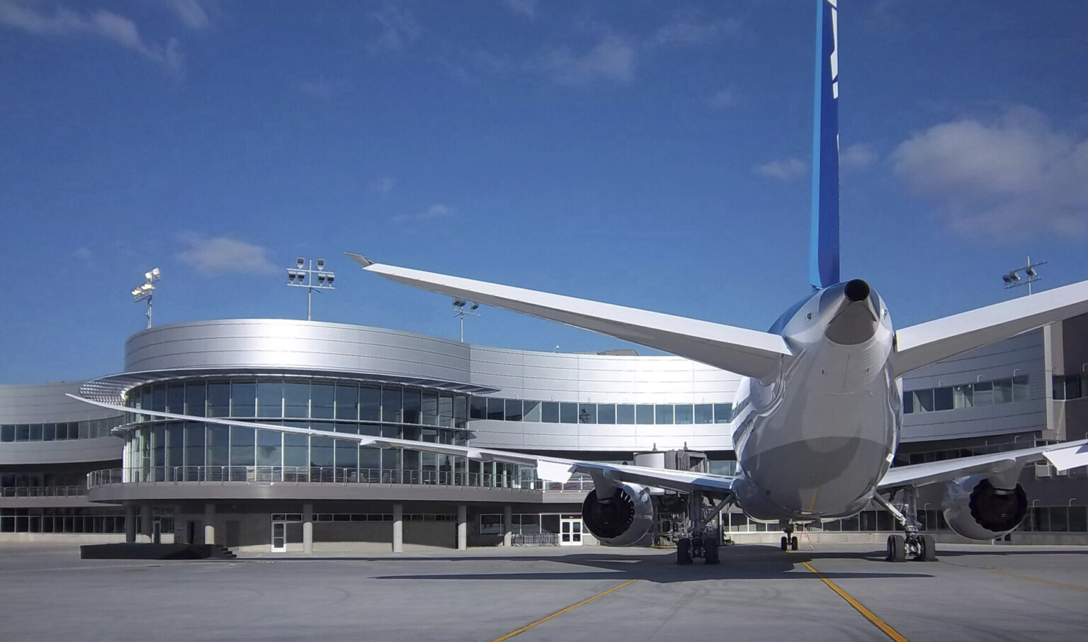Boeing Everett Delivery Center curving building with glass and silver panel facade with elevated walkway wraps around plane Boeing Everett Delivery Center curving building with glass and silver panel facade with elevated walkway wraps around plane