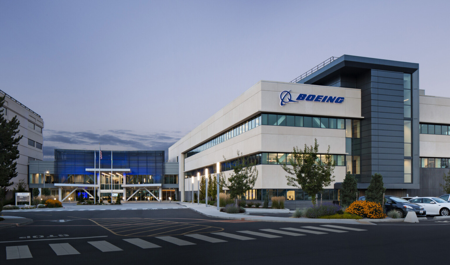 Boeing Seattle Delivery Center front entrance with logo on front of white wrapped facade. Blue recessed glass entry Boeing Seattle Delivery Center front entrance with logo on front of white wrapped facade. Blue recessed glass entry