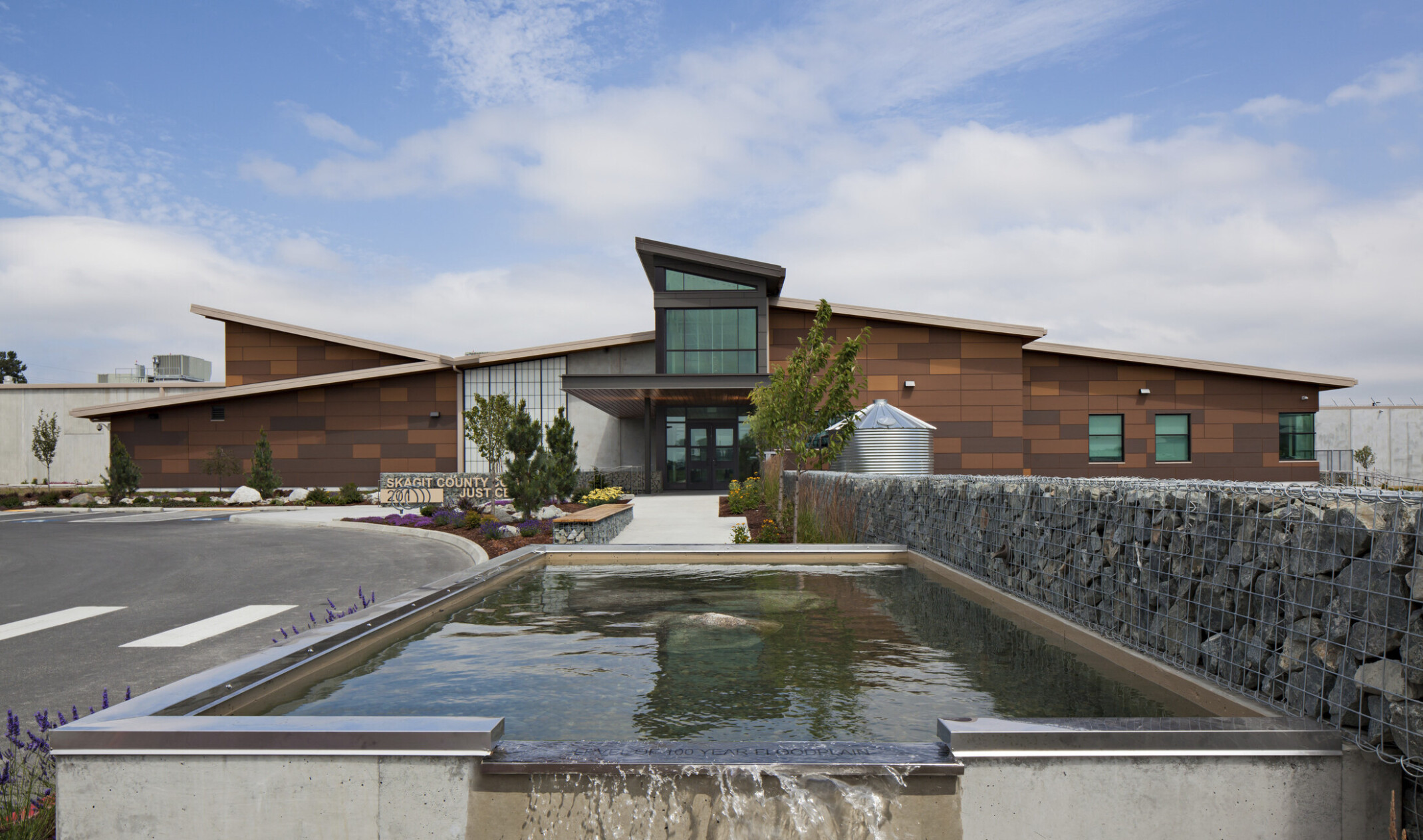 The Skagit County Community Justice Center, a stone building with central entryway. Front is water feature and stone gabion