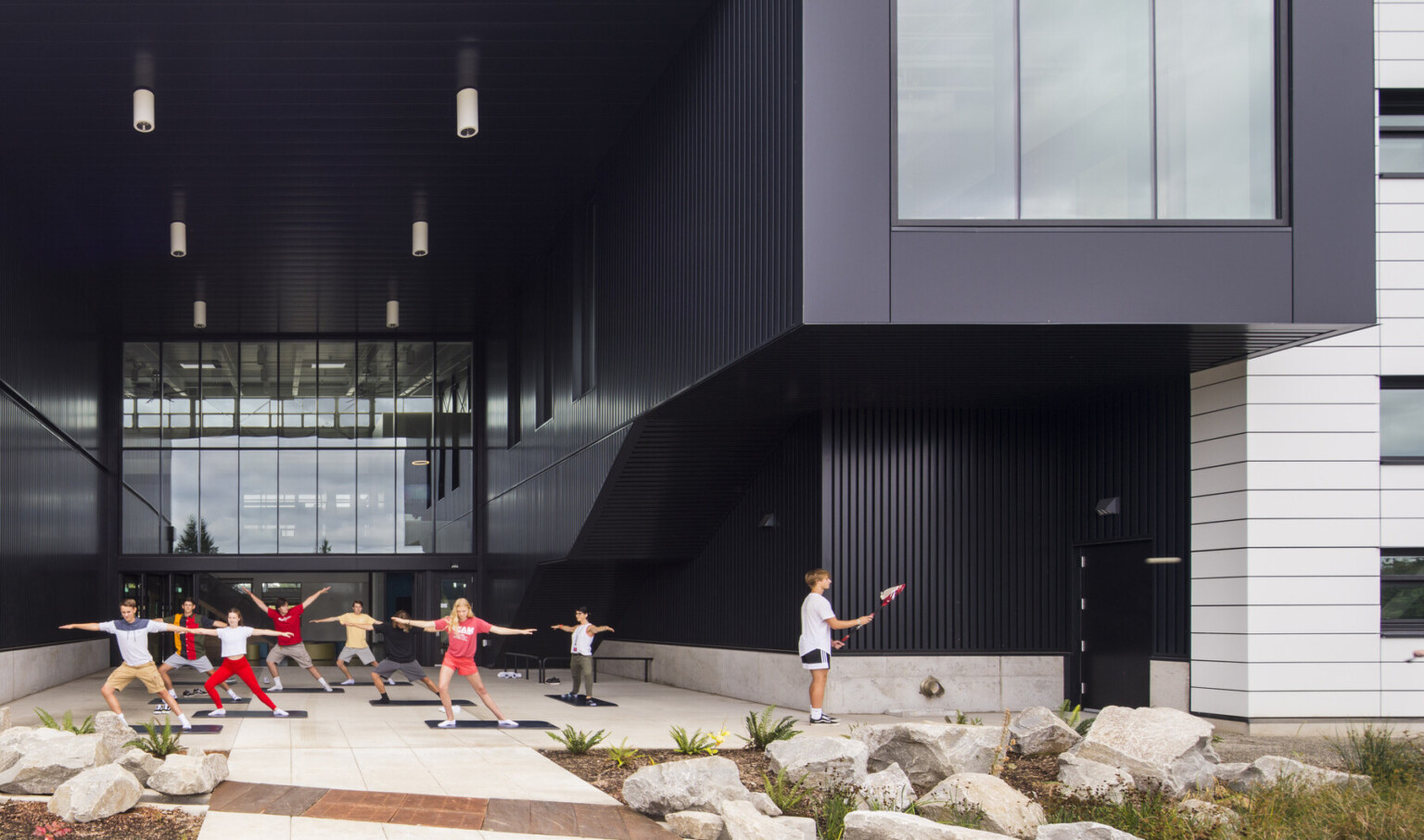Exterior view, atrium is recess and patio is covered. Right, the building extends in a black tunnel with large window at end Exterior view, atrium is recess and patio is covered. Right, the building extends in a black tunnel with large window at end