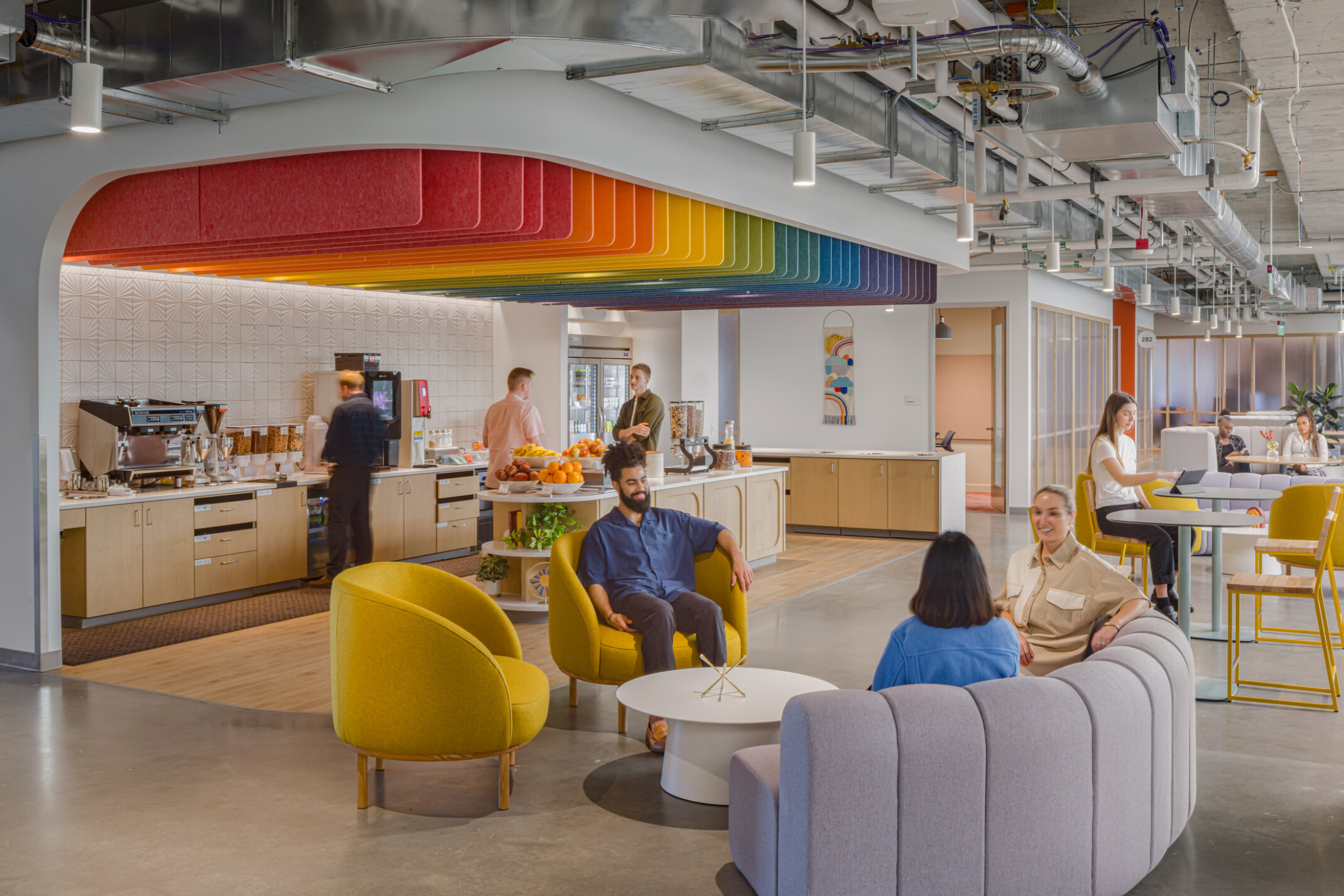 Vibrant seating area showcasing a rainbow ceiling over a coffee bar surrounded by seating areas with yellow chairs and plush couches