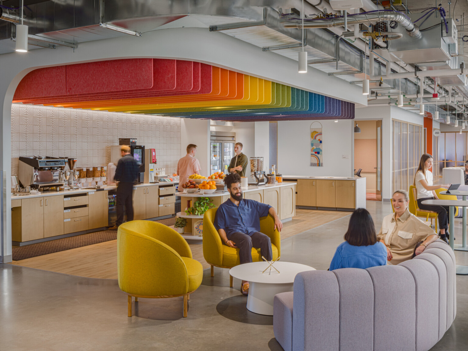 Vibrant seating area showcasing a rainbow ceiling over a coffee bar surrounded by seating areas with yellow chairs and plush couches