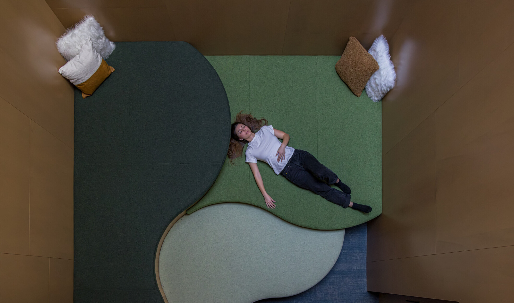 Woman lays in dim, relaxing room with lounging floor space