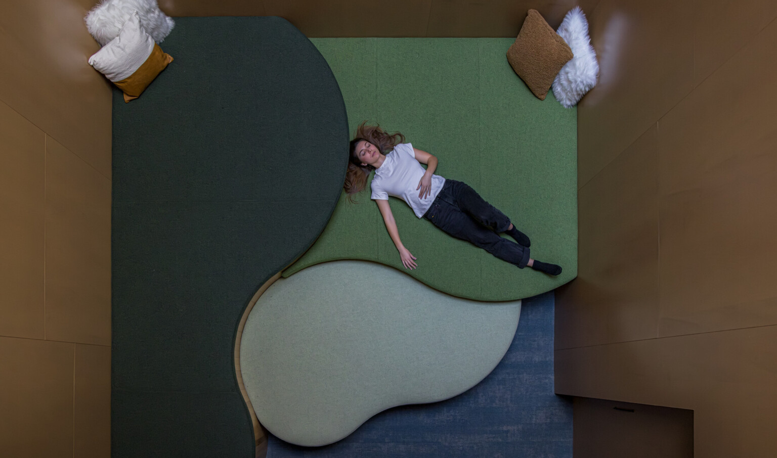 Woman lays in dim, relaxing room with lounging floor space