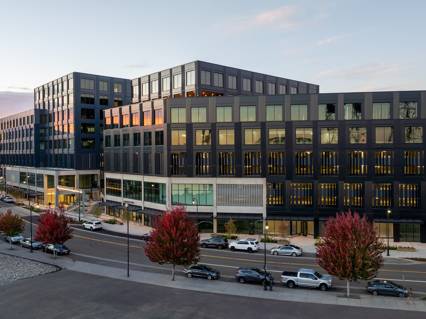 exterior view of mixed-use development in vancouver; dark grey facade highlighted by dusk sun