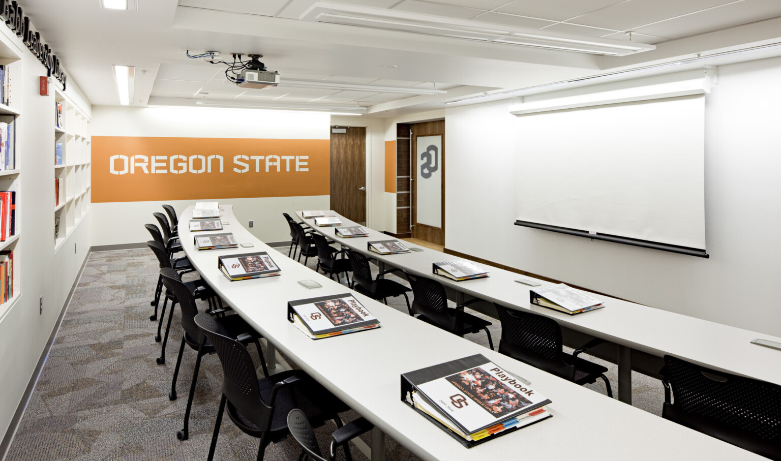 Room with built in bookshelves, orange stripe, rows of seating curving around screen, front, at Oregon State University