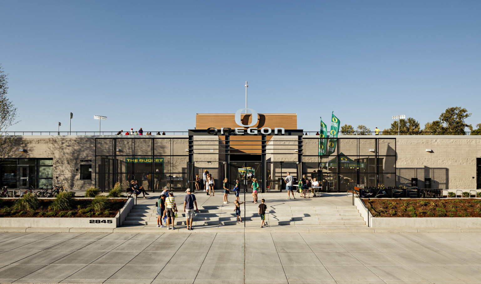 Papé Field entrance, 1 story concrete building with black gates and accents. Wood panels rise up at center with Oregon logo
