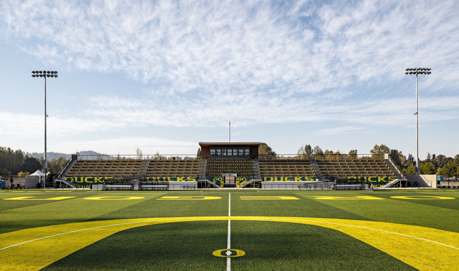 Papé Fieldseen from center line during game, green and yellow bleachers reading Go Ducks. Press box with canopy extending