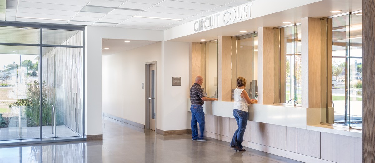 people standing at front desk station at goverment services building, open and welcoming design concepts welcomes visitors