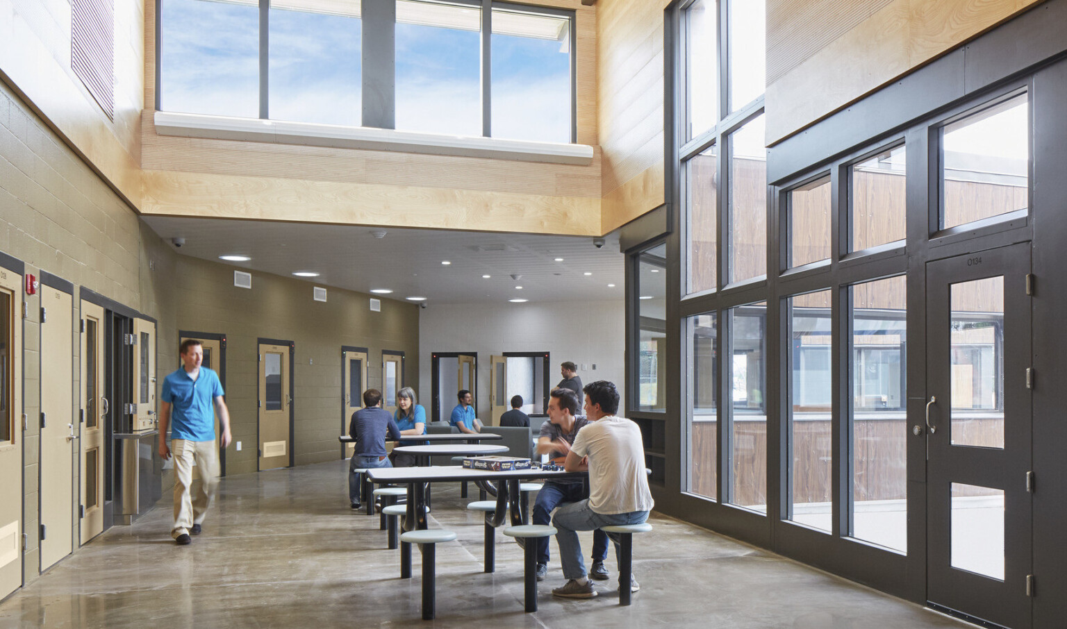 Oregon Youth Authority Maclaren Campus entry hallway. Black framed double height windows at entrance and wood upper walls