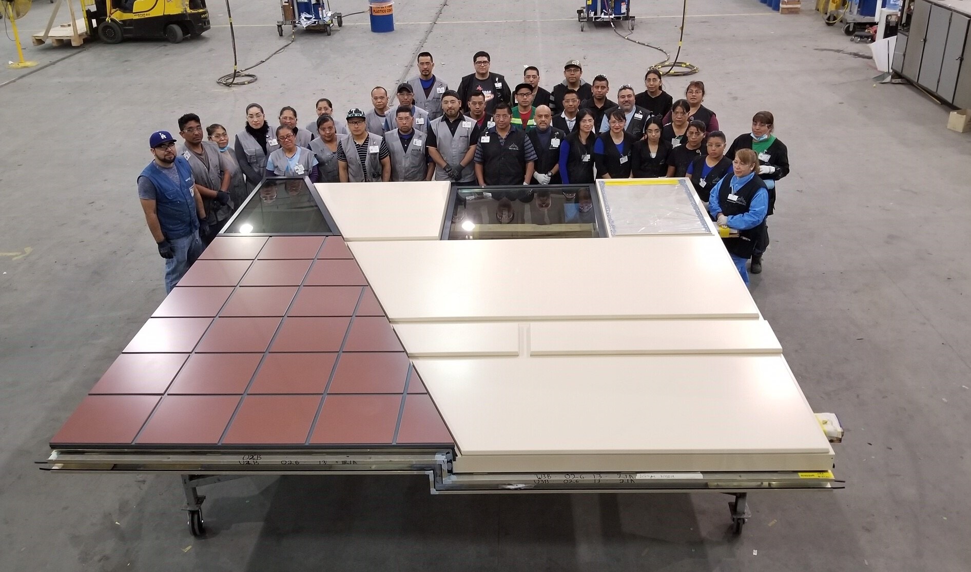 group gathered around a cream and maroon building panel in a large warehouse