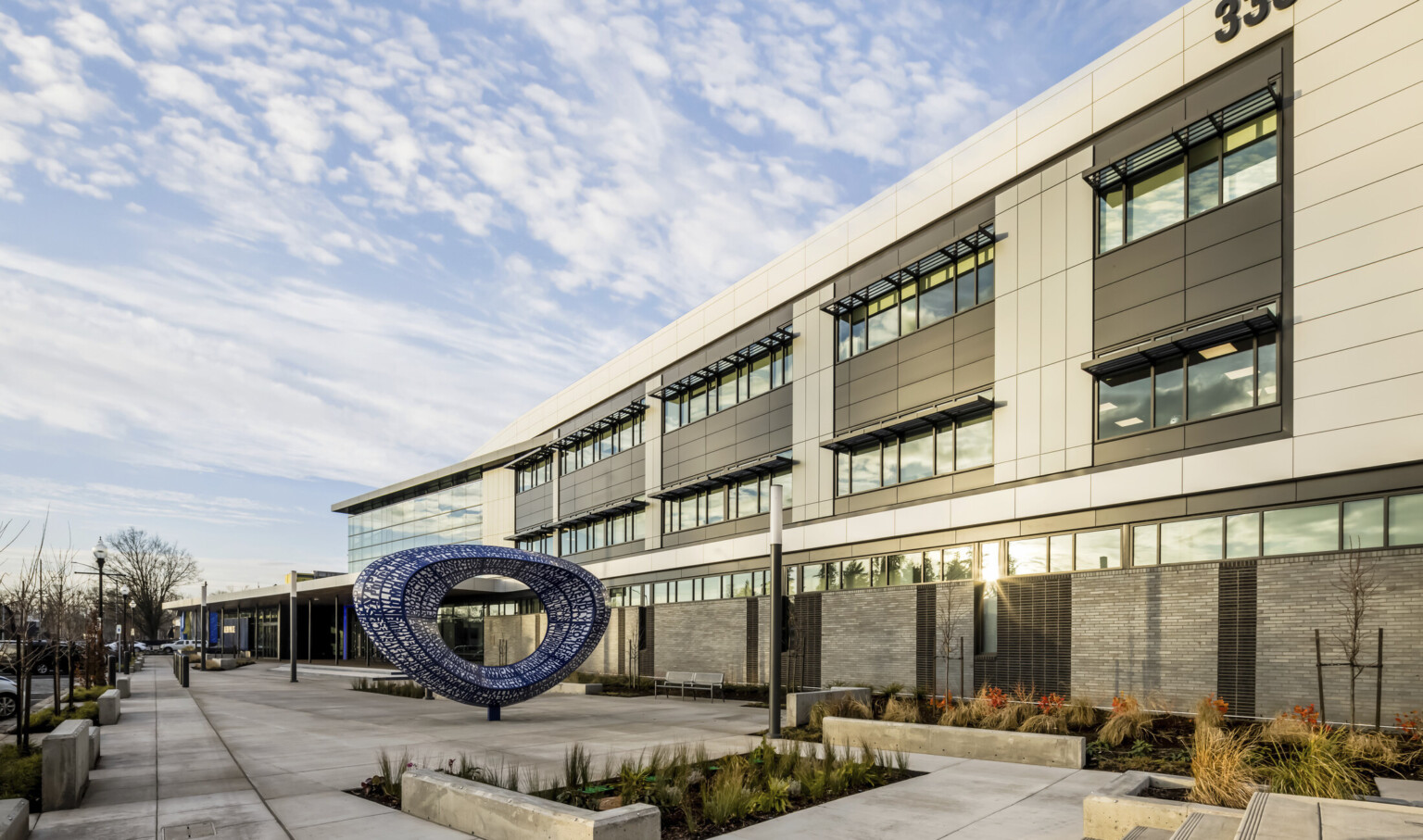 Sunlight reflecting on the windows of Salem Police Station with abstract sculpture near entrance
