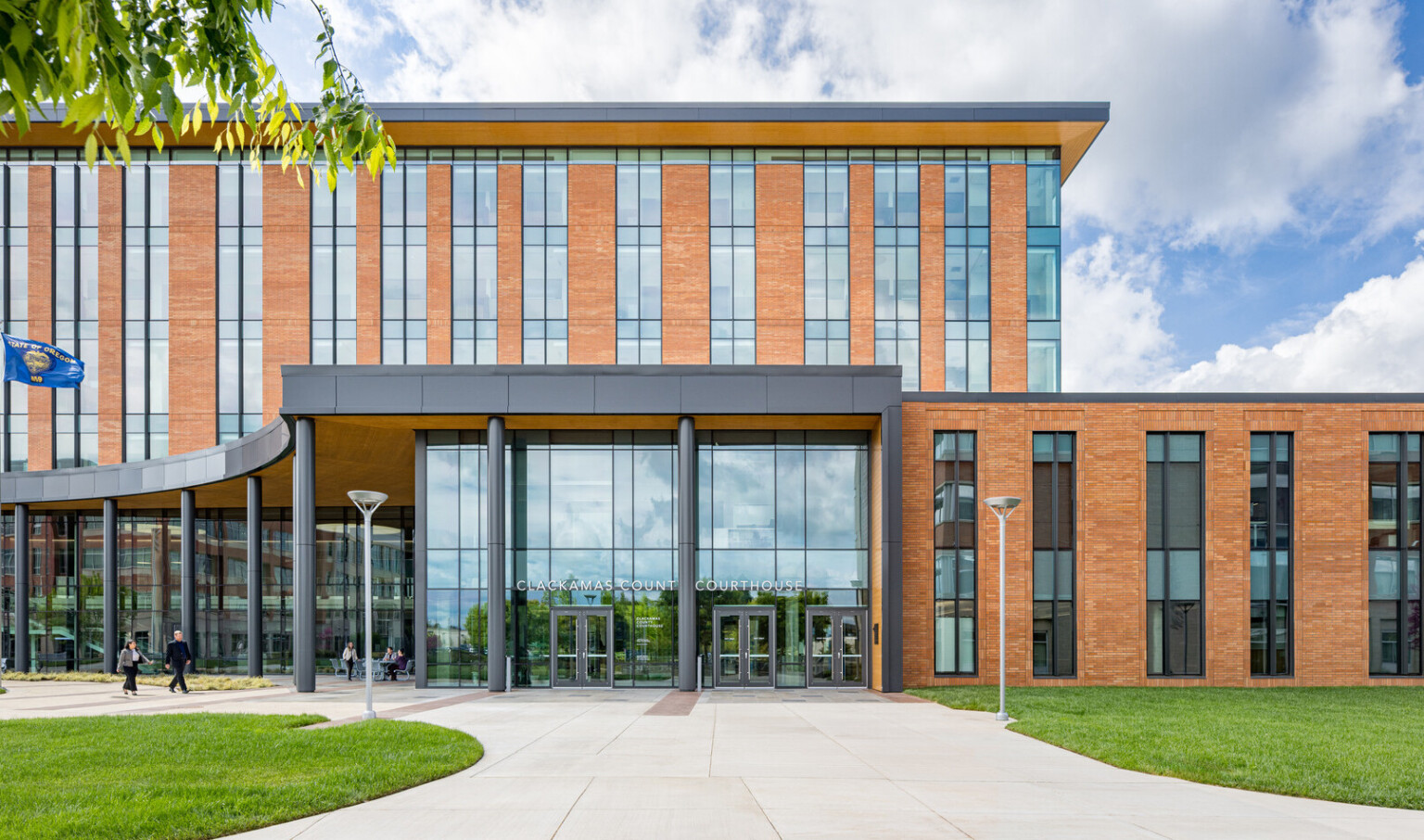 exterior photo of Clackamas County Courthouse; modern orange colored building with long and tall windows with an open glass entryway
