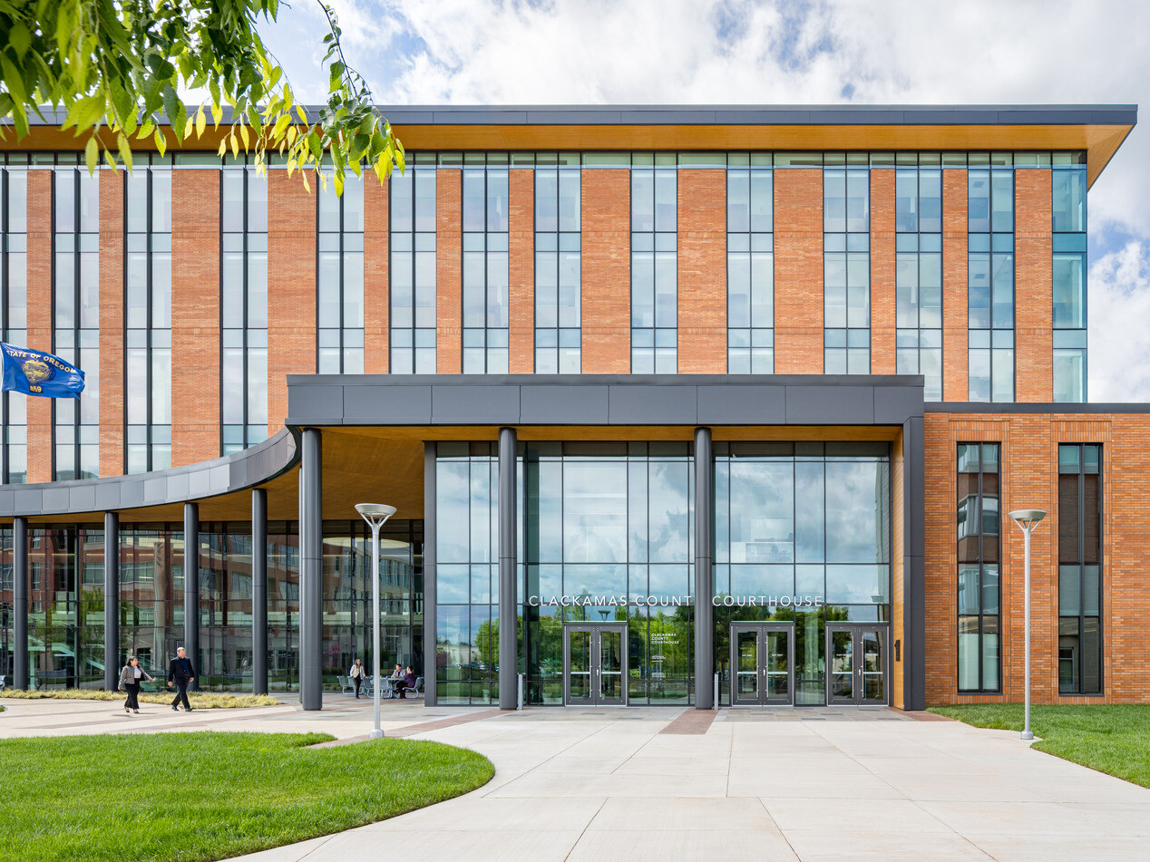 exterior photo of Clackamas County Courthouse; modern orange colored building with long and tall windows with an open glass entryway